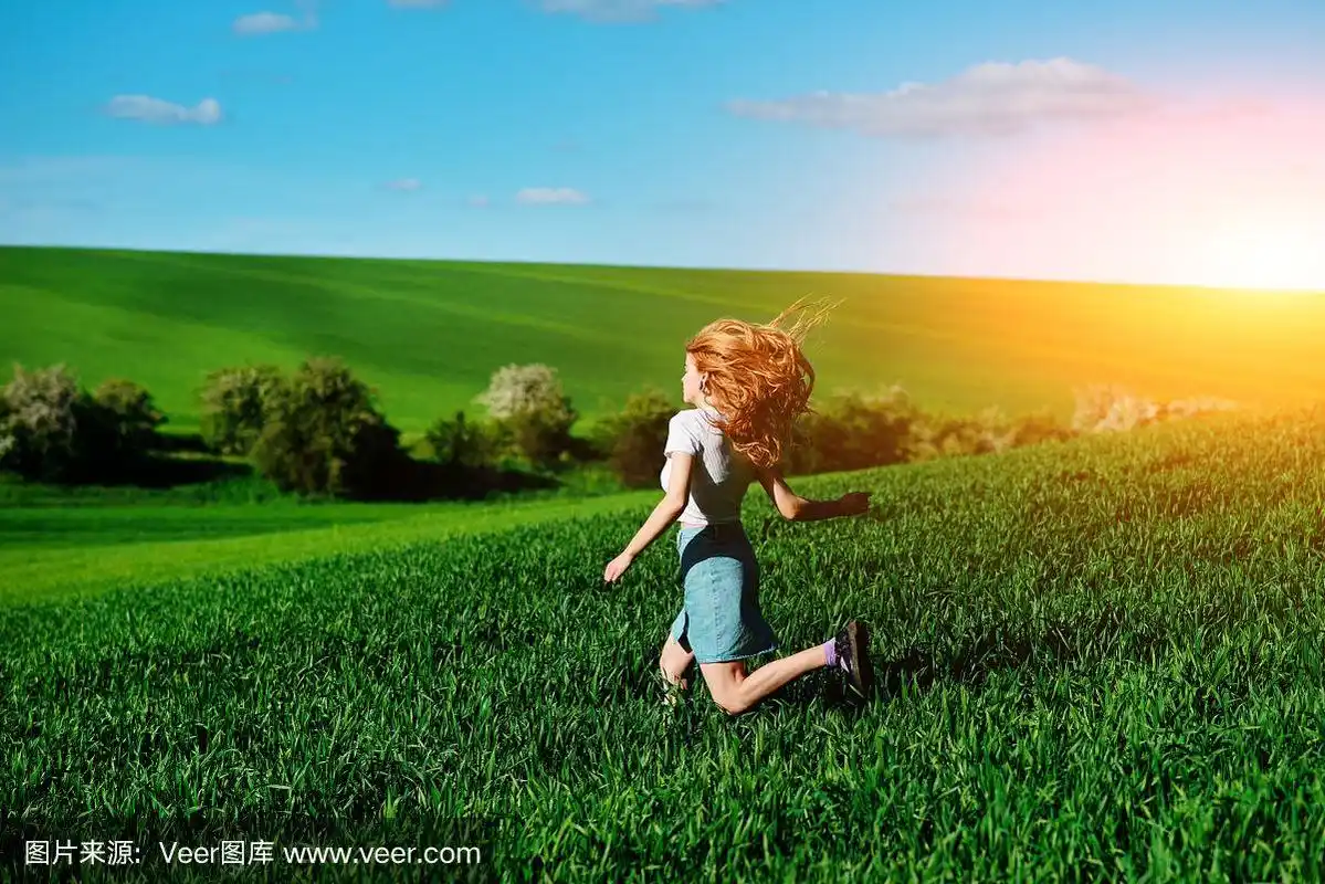 年轻美丽的女人在绿色的田野上奔跑