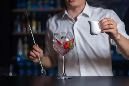 牛奶在投手酒杯在酒吧柜台上装满了冰块,草莓和薄荷叶.