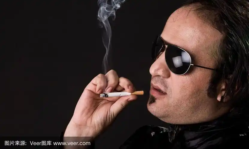 迷人的男人在黑色背景与香烟摆姿势