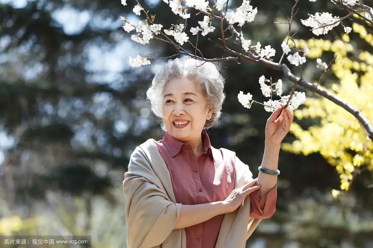 优雅的老年女人站在桃树下