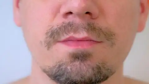 留胡子的男人正在吃红色草莓嘴巴特写