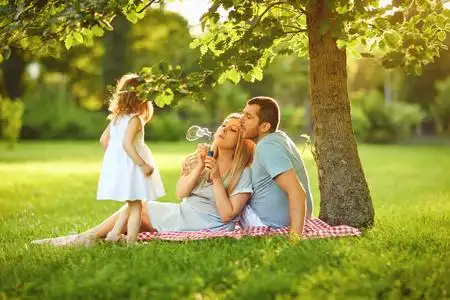 一家人带着孩子在公园的草地上照片