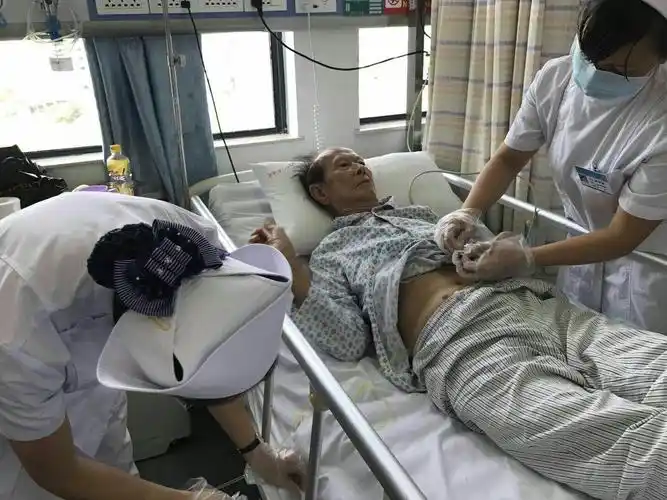 温馨的为活动不便患者更衣,弯腰细心检查尿管是否通畅.