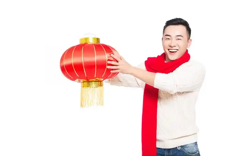 年轻男子手持中国红灯笼庆祝新年图片下载