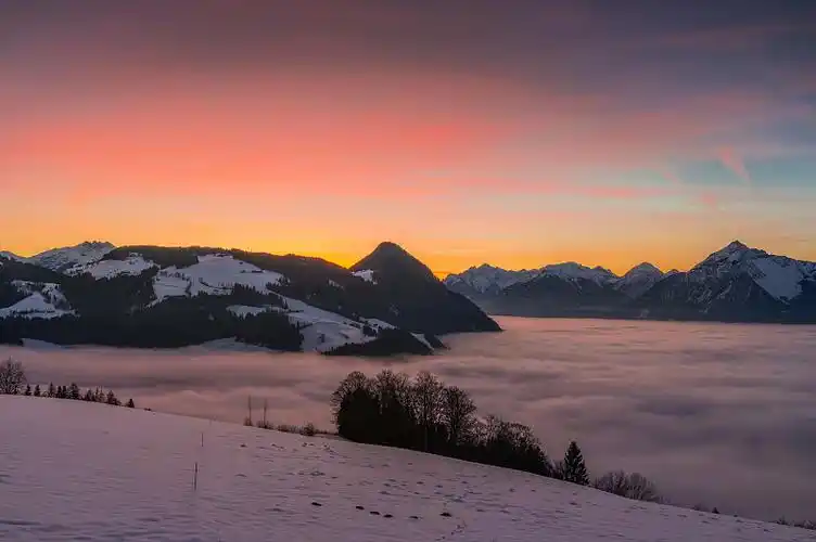 日落时,雪山笼罩着云朵图片下载