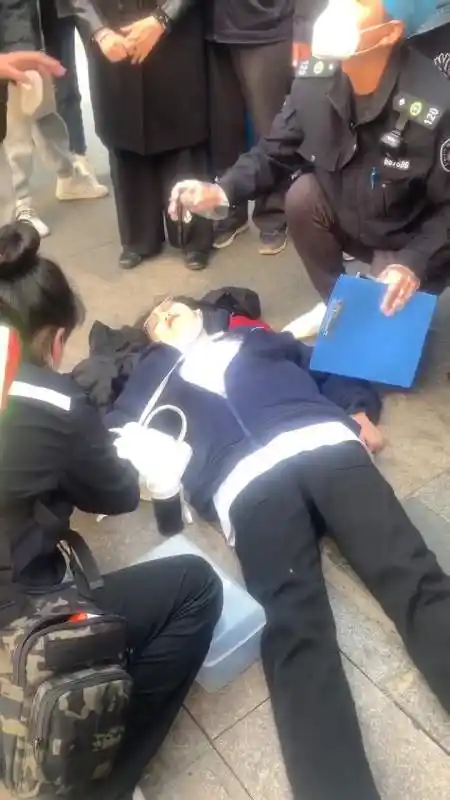 山东青岛,一位年轻人单膝跪地,为昏厥的女子进行心肺复苏抢救