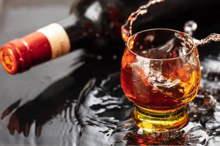 一瓶红酒加酒杯水溅落在黑色的倒影上