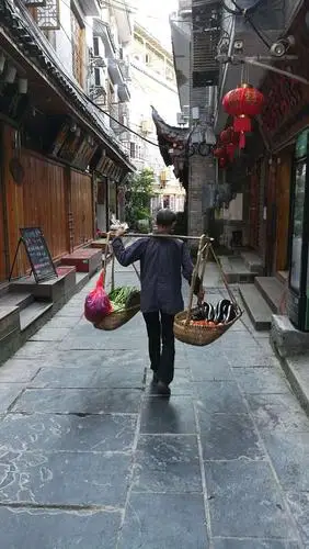 清晨走在古城青石板街巷挑担卖菜的农民.