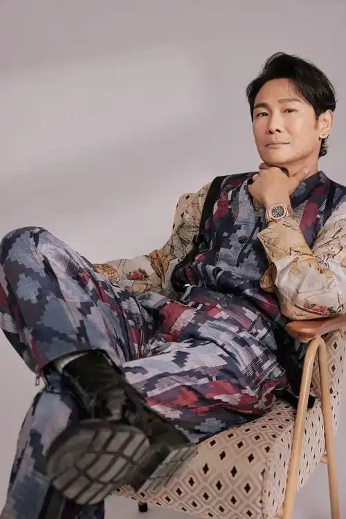 照片中的杜德伟身穿暗色印花马甲套装,内搭棕色系花纹衬衫,明暗搭配恰