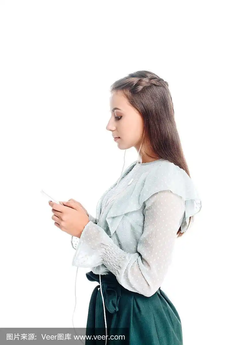 年轻女子一边用智能手机一边用耳机听音乐的侧面图