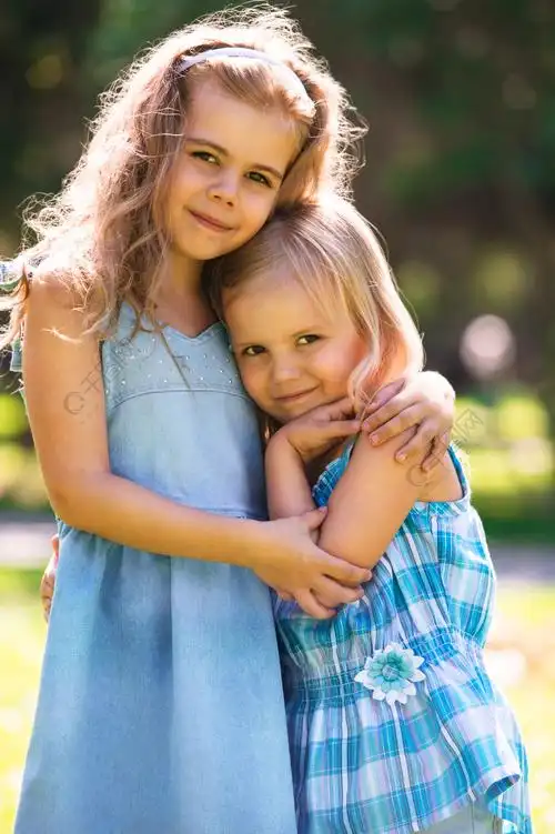 两个拥抱可爱的小女孩的室外肖像