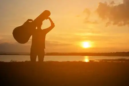 快乐的女人和吉他天空日落时的剪影照片
