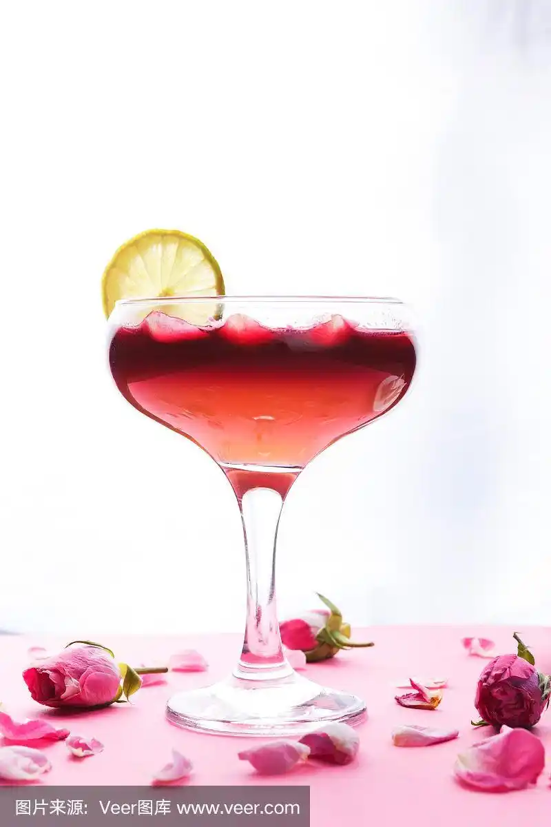 粉红背景的香槟杯中的玫瑰鸡尾酒
