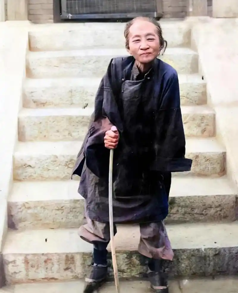 1915年,一位慈祥的老太太拄着一根木棍,眯着眼睛对着镜头微笑!