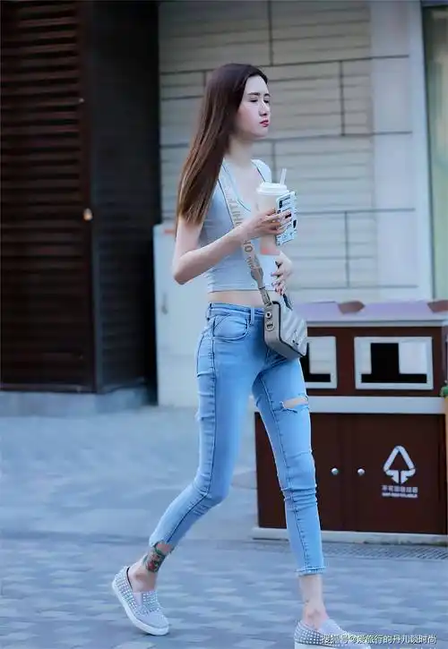 小姐姐身穿蓝色破洞牛仔裤修身的版型秀出好身材,搭配灰色v领短t恤