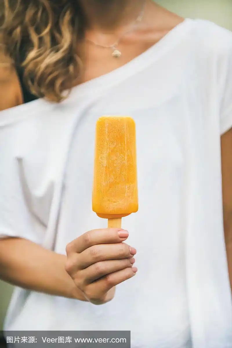 女人手里拿着芒果柑橘冰淇淋冰棍