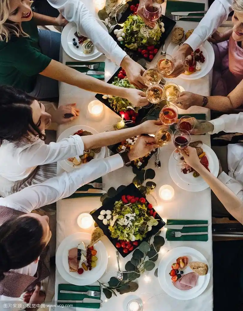 在一个室内聚会上,人们坐在一张桌子旁,碰杯顶视图