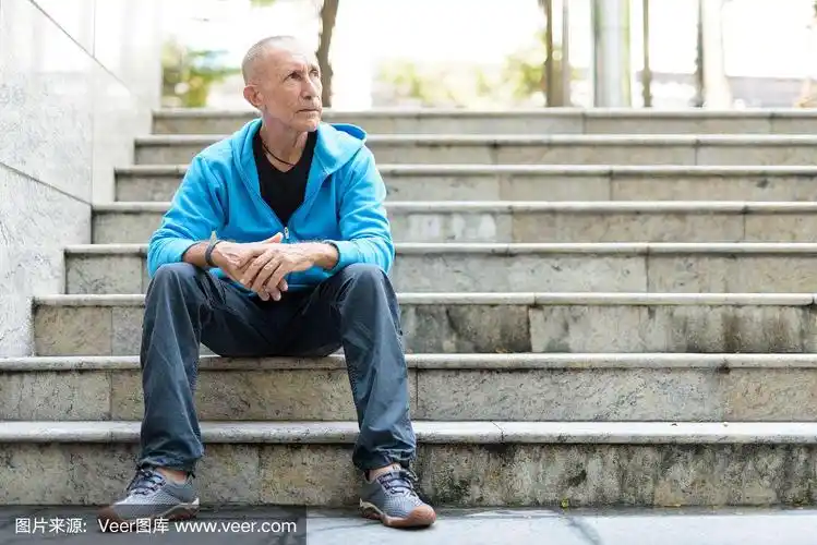 全身拍摄的光头老男人坐在泰国曼谷的楼梯上思考