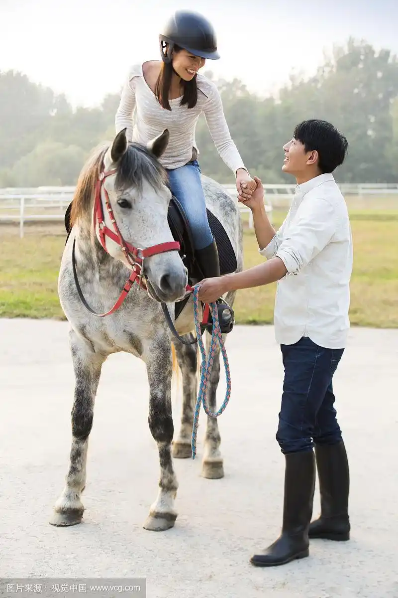 年轻情侣在马场骑马