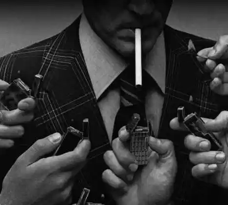 一个男老外叼着一根烟,下面有很多个打火机给他点烟