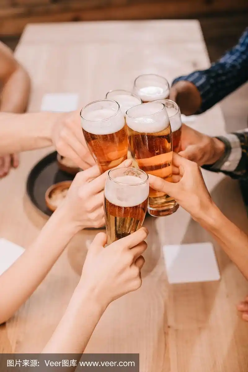 来自不同文化背景的朋友在酒吧里喝着啤酒碰杯