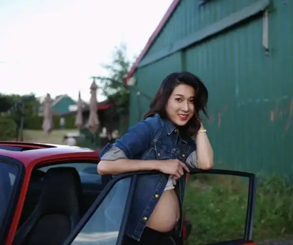 钟嘉欣倚在车门上,对镜展现迷人笑容,很难相信这已经是她怀的第三个
