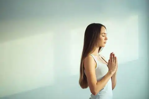 瑜伽的侧面观在公园的草地上举起双手做合十手势011高级女子在公园