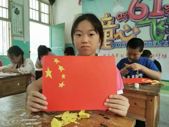 孩子们展示制作好的国旗剪纸作品全班同学制作完成国旗和党旗