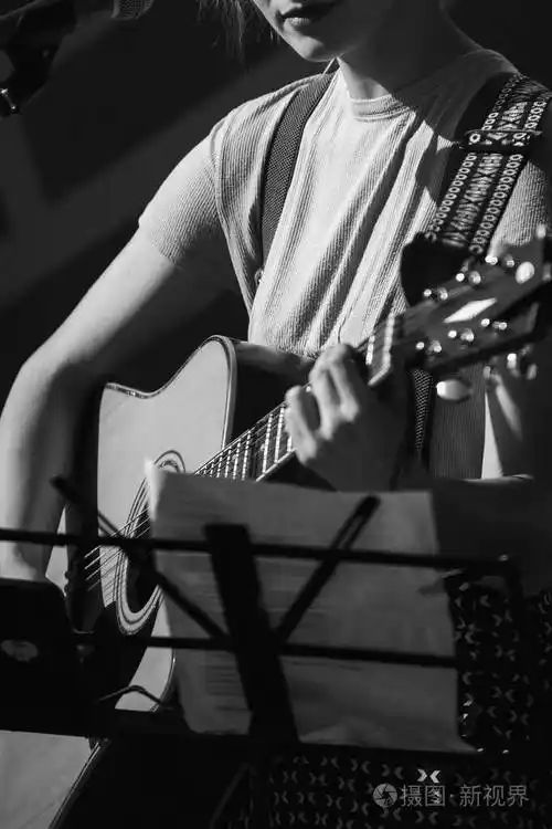 这个女孩在黑色背景上弹吉他黑白照片