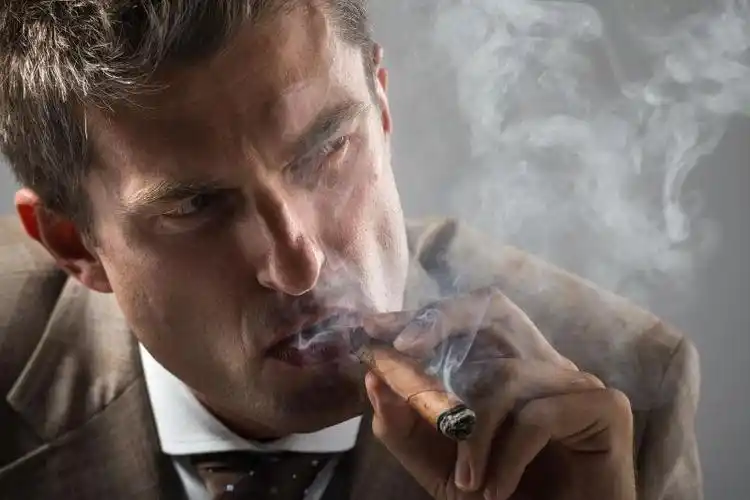 戴帽子的年轻男人抽雪茄