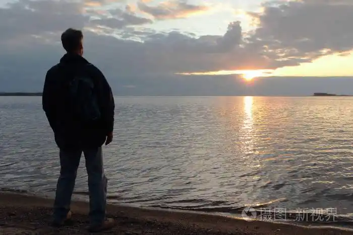 男人站在河岸边在日落