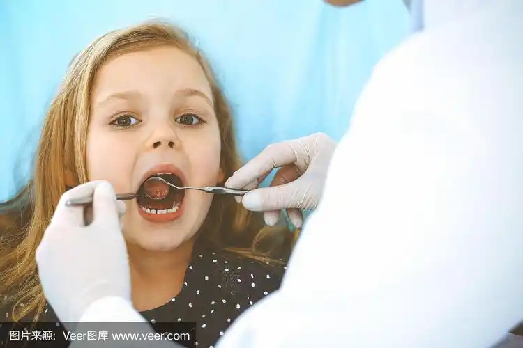 小女孩张大嘴巴坐在牙科椅上接受医生的口腔检查.拜访牙医的办公室.