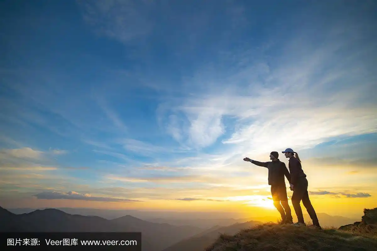 这对夫妇在山上做手势,背景是风景如画的夕阳