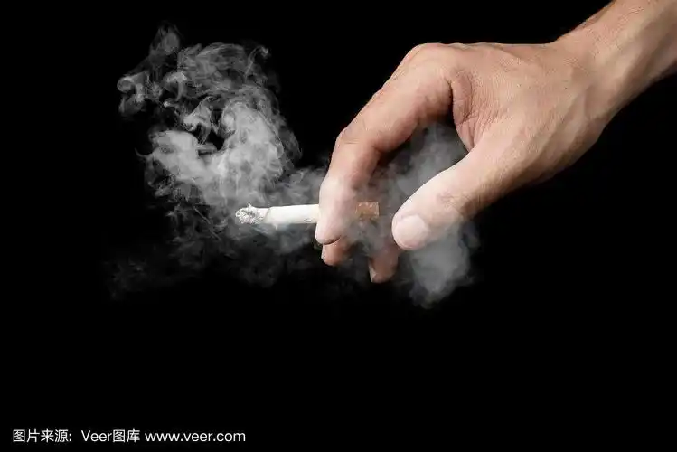 手握香烟的男人在黑暗中孤立地吸烟,在黑色的背景下