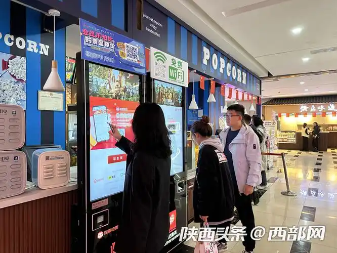 横店电影城西安中贸店自助取票机前,观众排队取票.