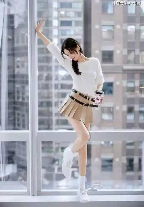 杨颖身着白色针织衫和卡其色百褶短裙,搭配白色马甲,整个造型既清新