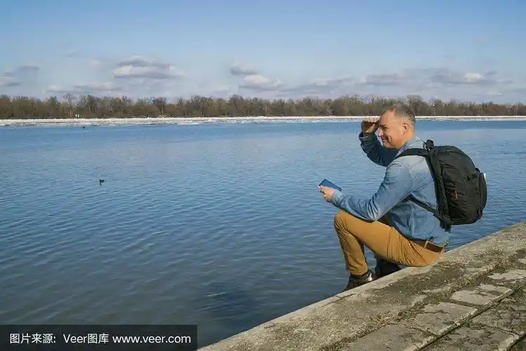 一个成熟的男人坐在湖边欣赏风景