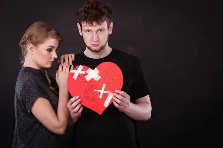 夫妻心碎难恋的概念伤心不幸福的夫妻男女手拿纸红心用石膏绷带固定