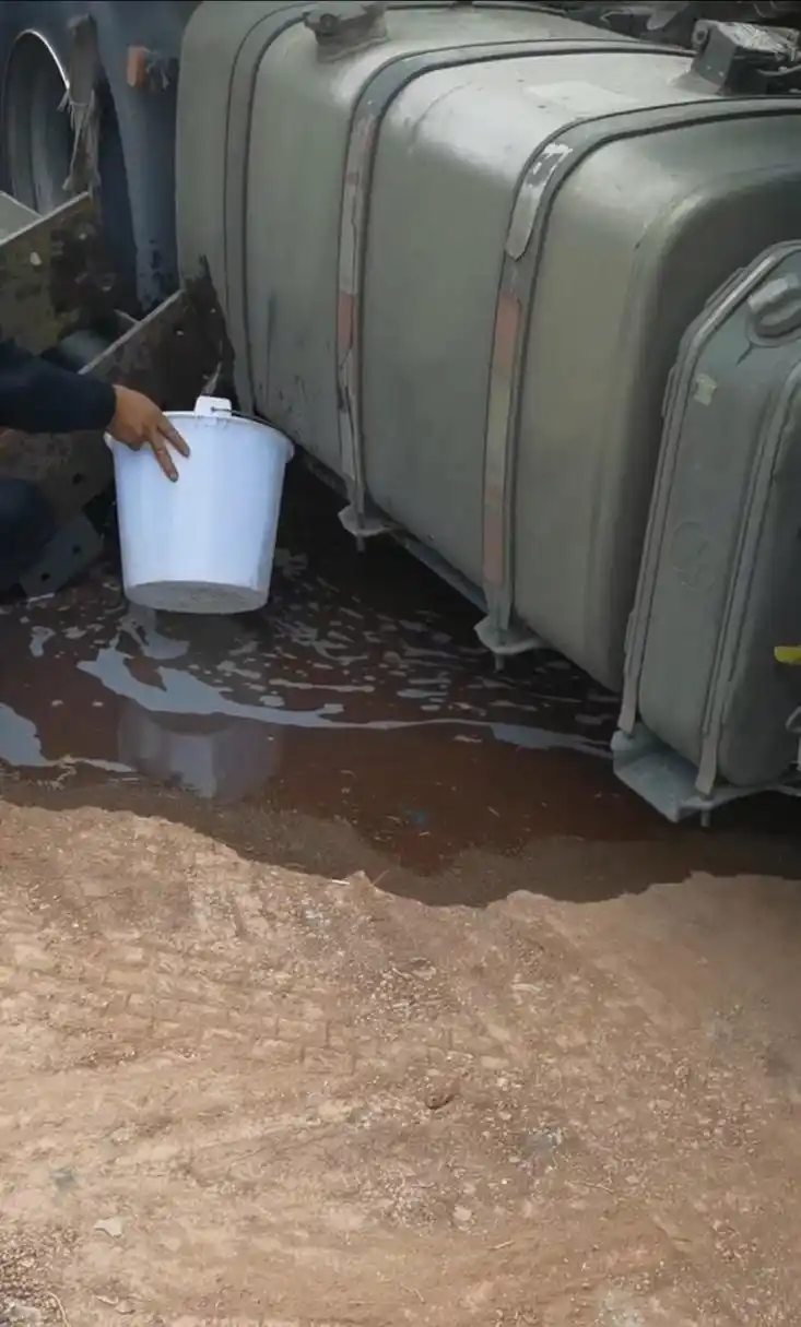 大货车油箱被磕到漏油了,小伙子拿了个白桶接油,我还说能接多少是多少