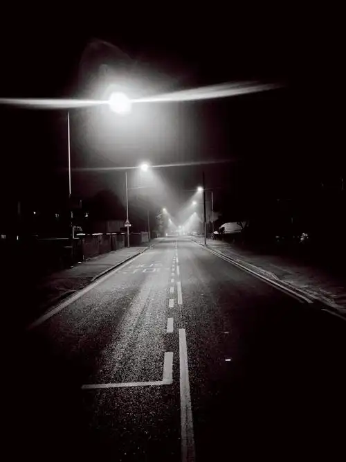 雾天夜色朦胧路灯的光穿过雾洒在地上形成一个个小舞台一条孤独的路